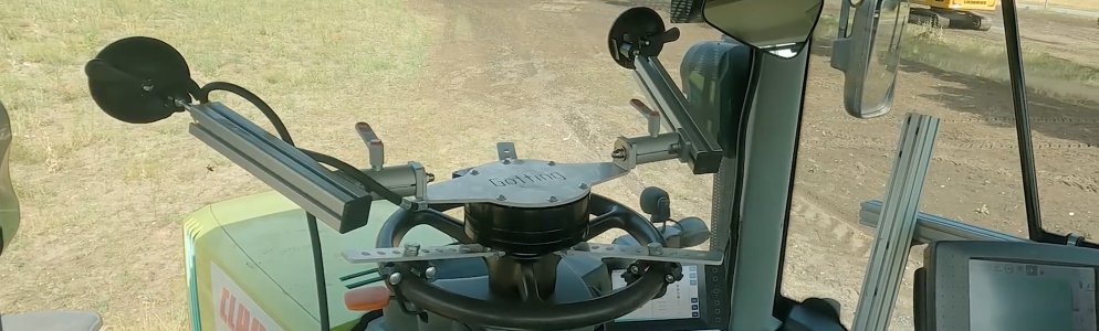 Photo from the cabin of a tractor with the steering actuator that controls the steering wheel and whose construction is supported by suction cups on the windshield