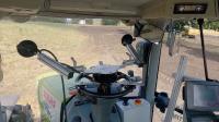 Photo taken from the tractor, the automated steering wheel can be seen, through the windshield you can see the test site, on which an automated excavator is driving on the right edge of the picture